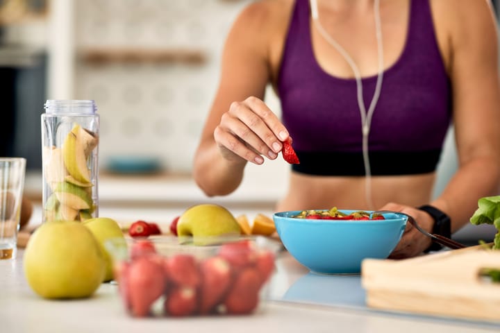 mujer deportista cocinando con alimentos saludables 